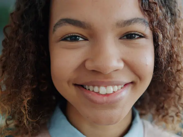 A young woman with curly hair smiling with bright teeth