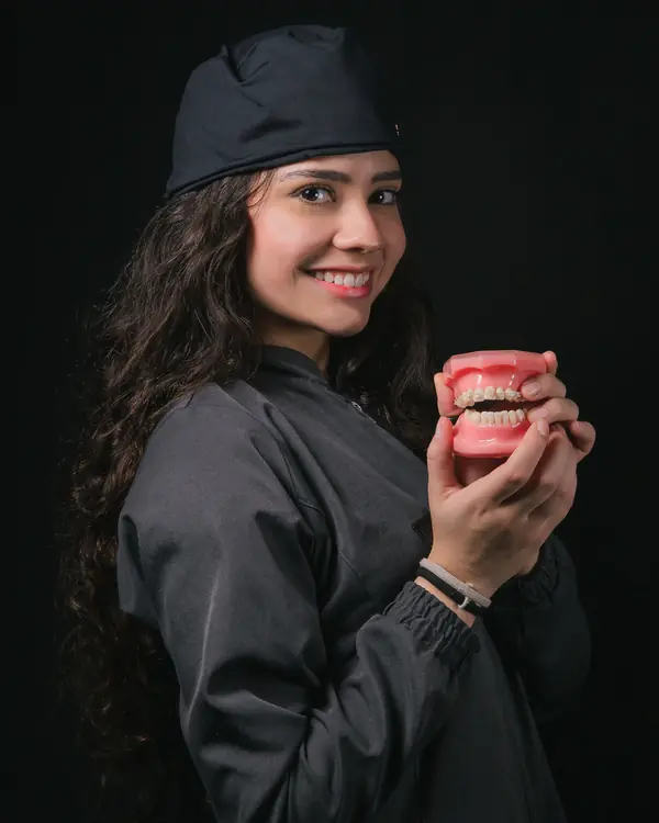 Dr. Elena Varga holding a model of a smile in the studio