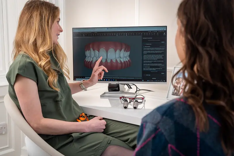 A dentist reviews a 3D smile design on screen with a patient