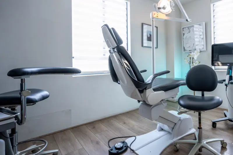 A bright treatment room with a modern dental chair and large windows
