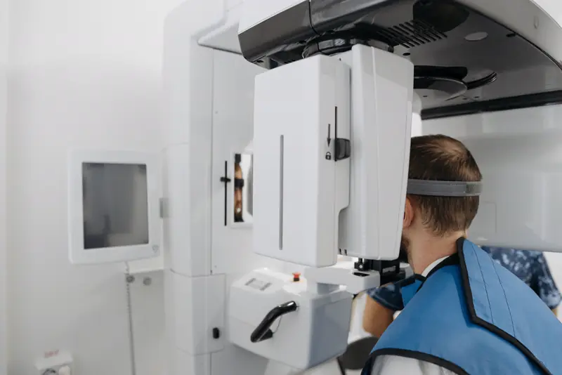 A patient stands in a panoramic X-ray machine