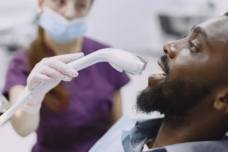 A hygienist scans a patient's teeth with a handheld 3D scanner