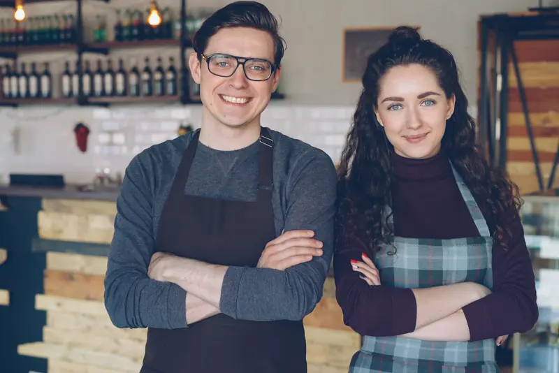 Mara and Theo, the founders, standing behind the café counter in aprons