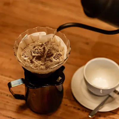 Pour-over brewer with fresh grounds on a wooden counter