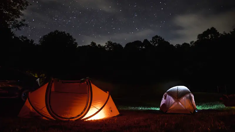 Tents glowing at a campsite under a starry sky