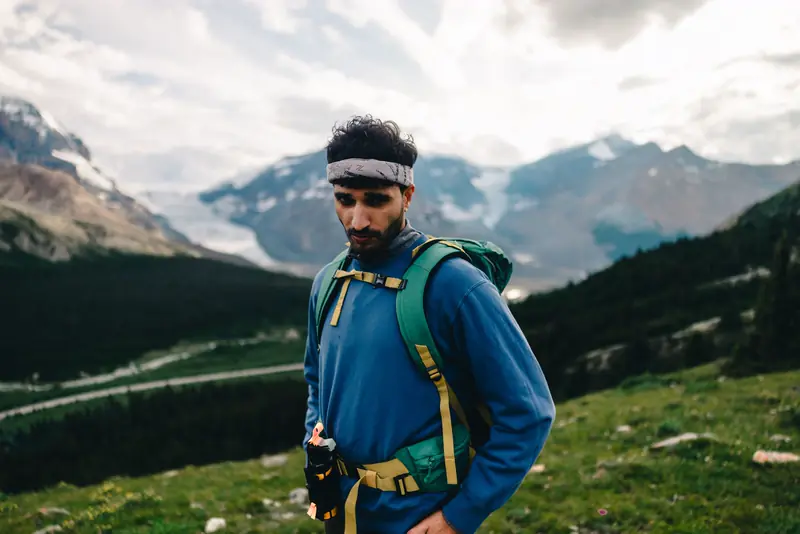 A hiker with the pack pauses on a mountain trail