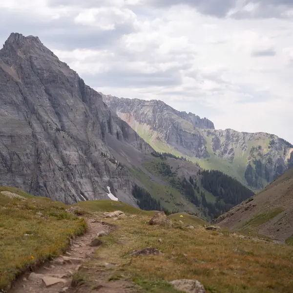 A trail climbs toward a steep peak in the San Juan Range