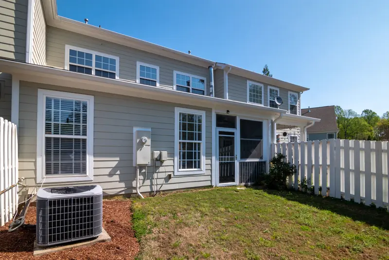 Outdoor air conditioner unit behind a two-story home