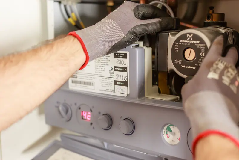 Technician's gloved hands adjusting a heating system