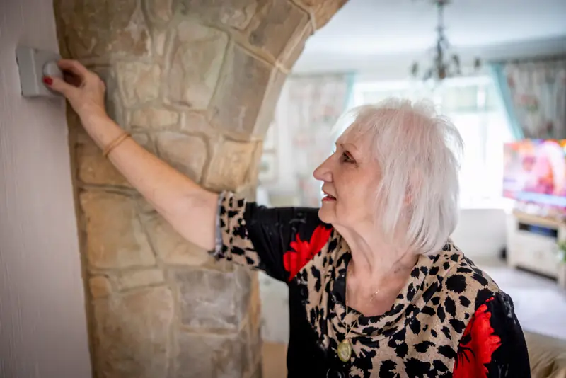 Woman adjusting the thermostat in her living room
