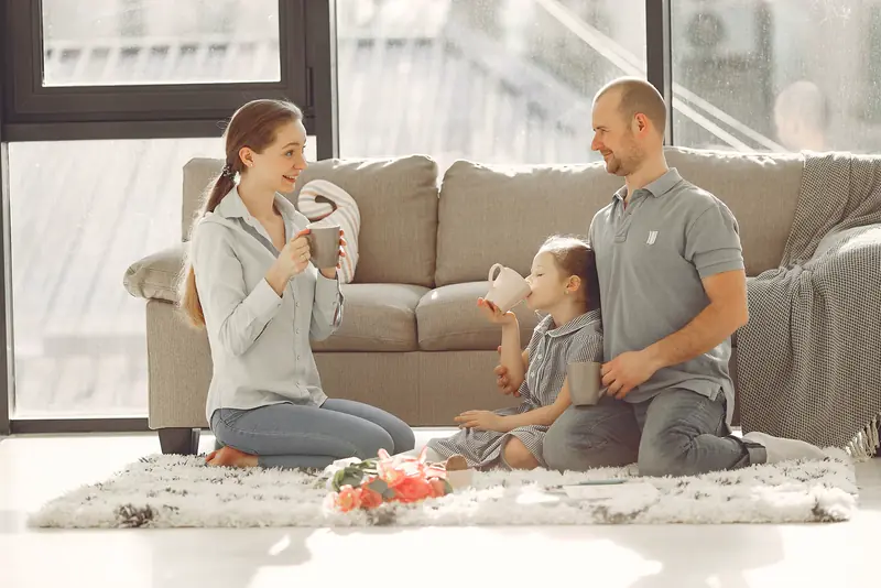 Family sitting on a cool living room floor, laughing