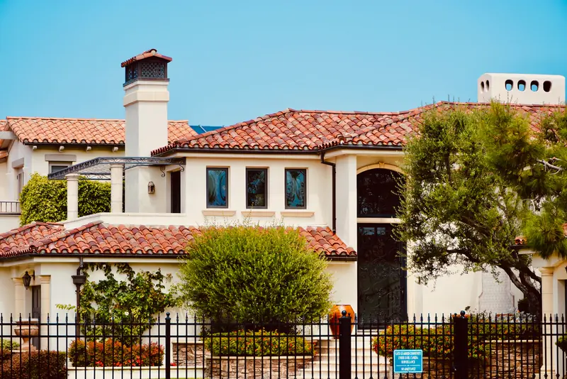 Two-story stucco home with a red tile roof and desert landscaping