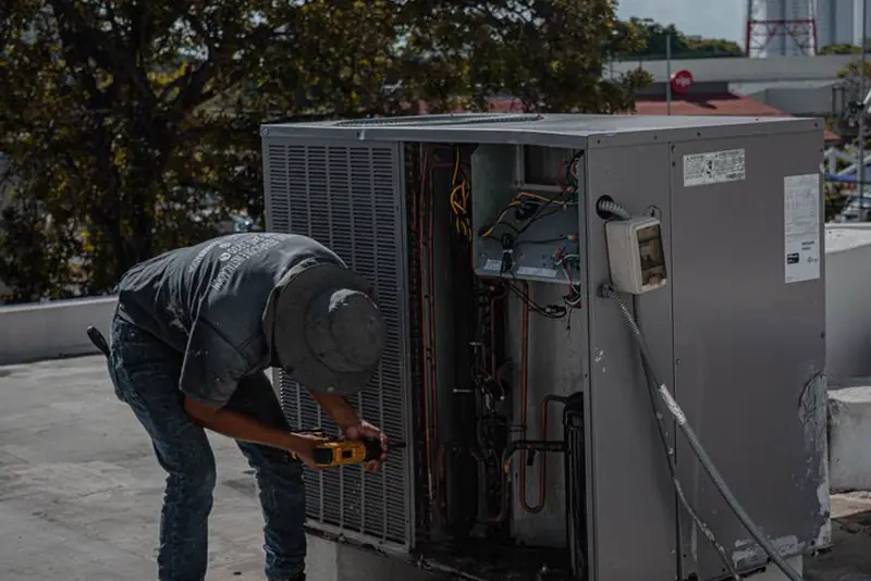 Technician testing a rooftop air conditioner in the sun