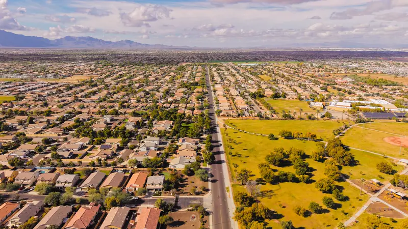Aerial view of a Phoenix-area neighborhood with tile roofs and a long straight road