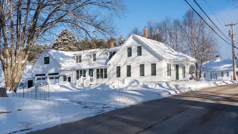 White New England farmhouse after a snowstorm, under a clear blue sky