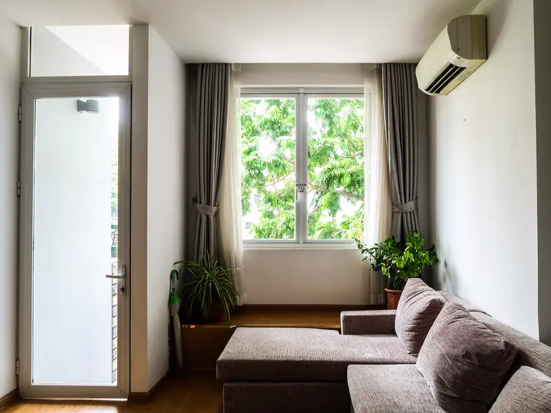 Sunlit living room with a ductless wall unit mounted high above the window