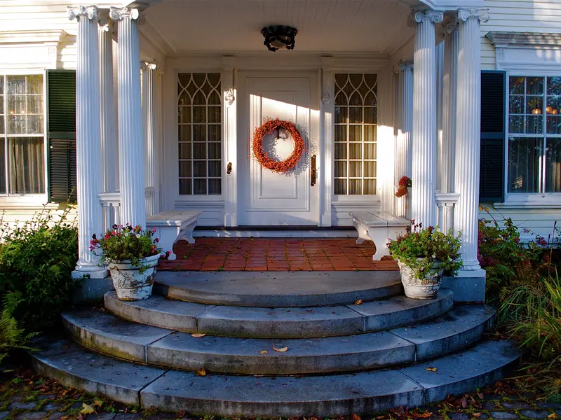 Columned front porch of a Greek Revival home with a fall wreath