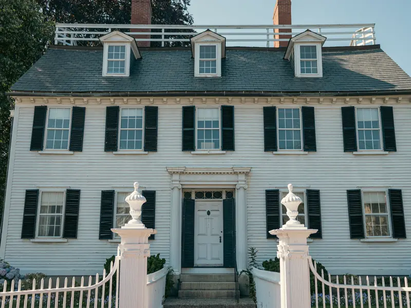 White colonial home with black shutters and a picket fence