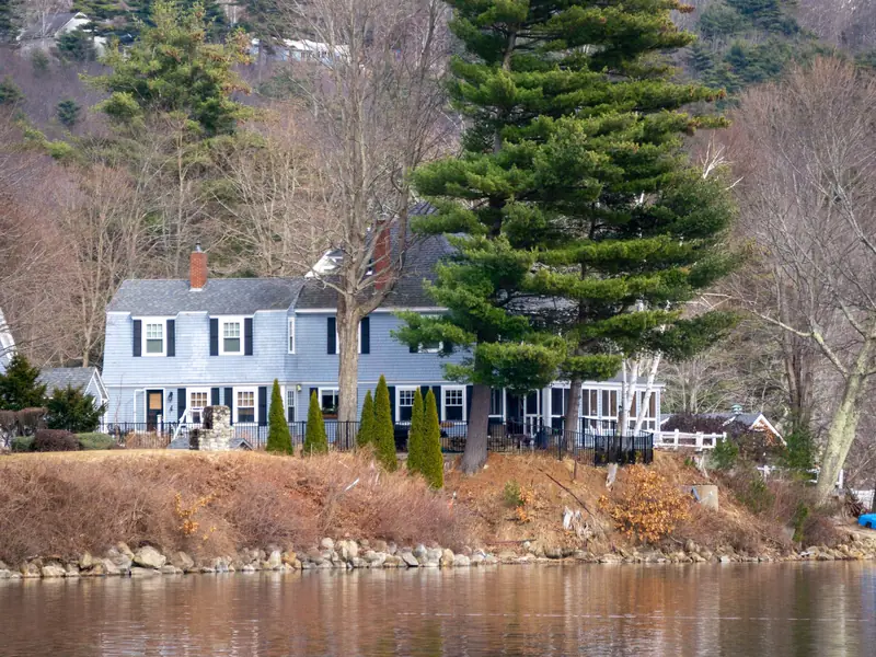 Blue lakeside house among tall pines in early spring