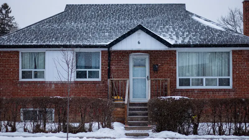 Brick ranch house with snow on the lawn and roof