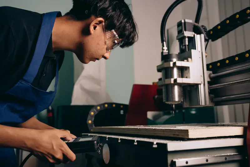 A machinist in safety goggles operates a CNC machine