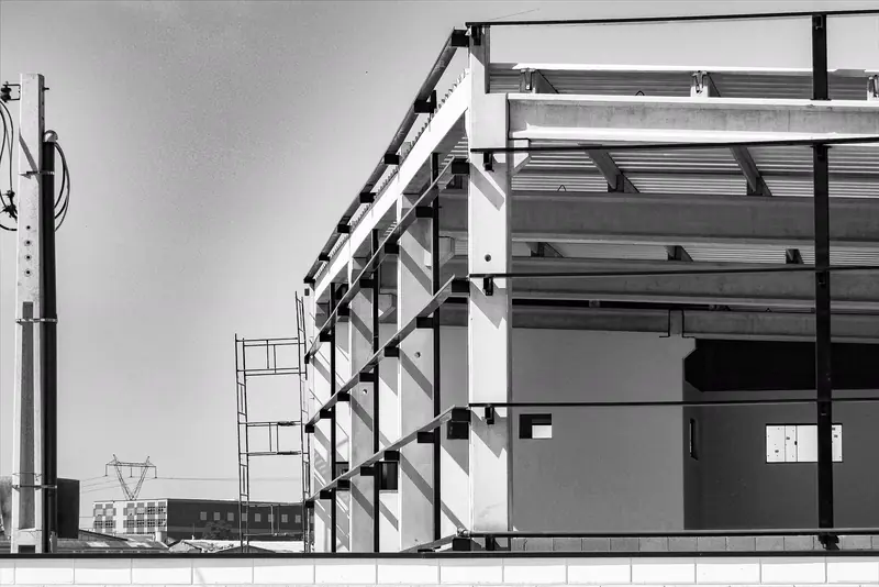 A steel-frame building under construction in black and white