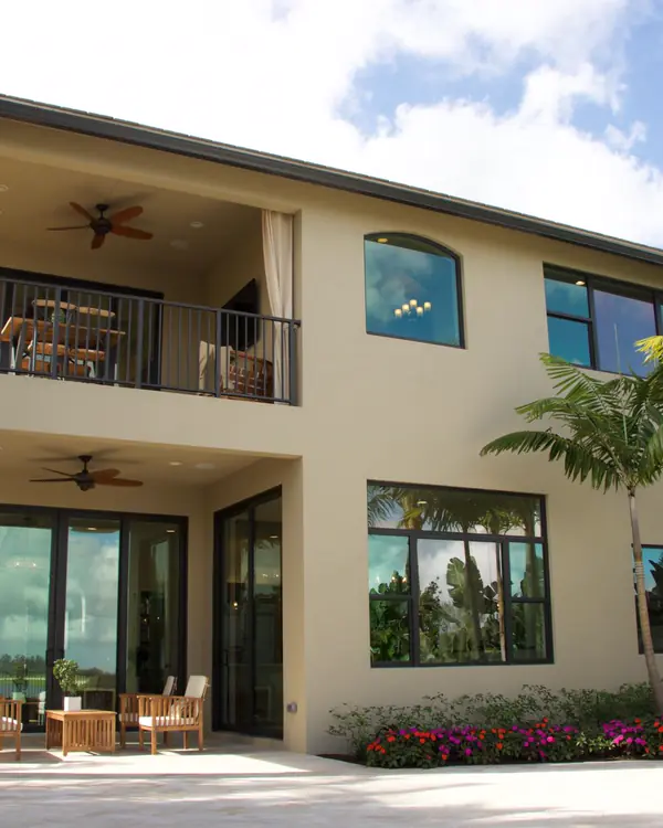 Two-story Tampa home with a balcony, a shaded patio and a palm garden