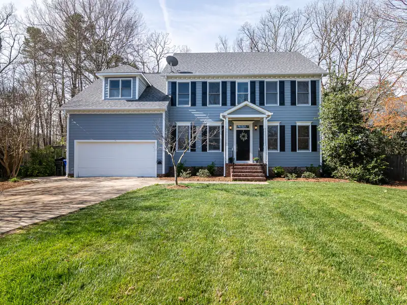 A two-story blue house behind a freshly mowed front lawn with clean stripes