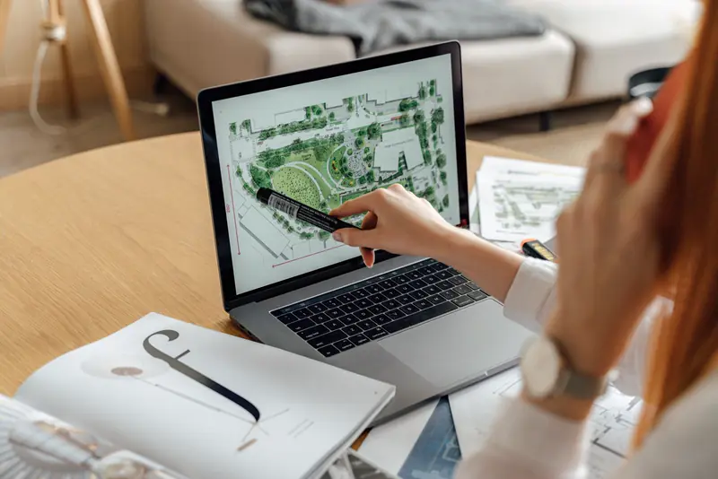 A designer reviewing a garden site plan on a laptop