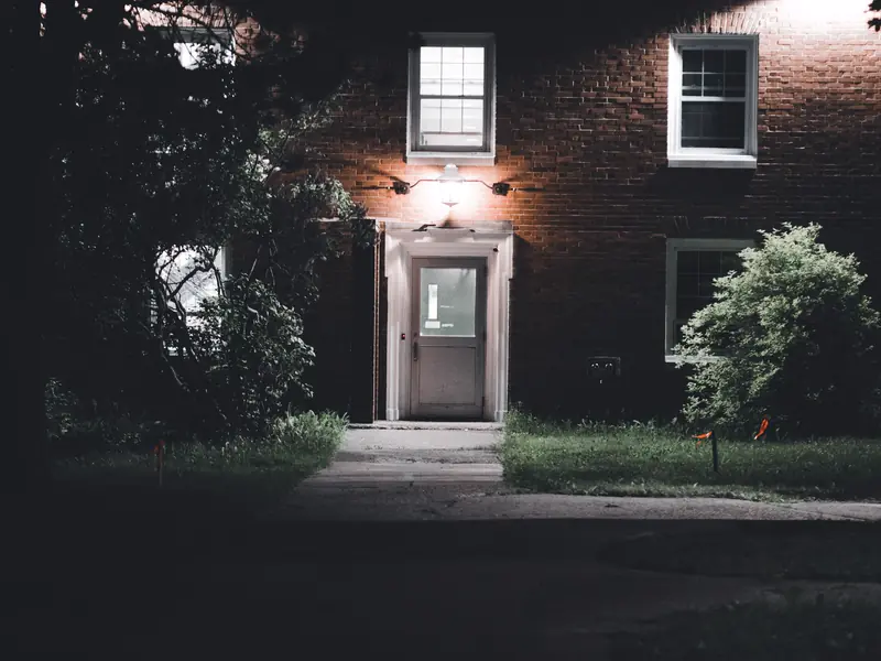 A brick house entry at night with soft light on the facade and path
