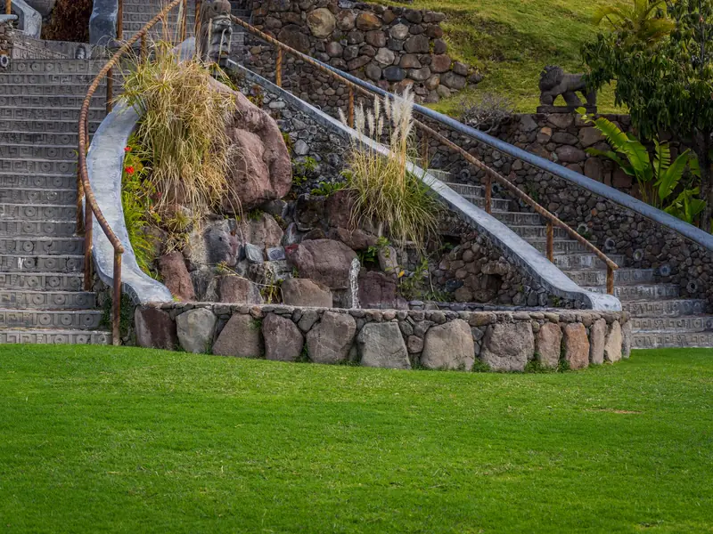 Curving stone steps and boulder walls climbing a planted hillside above a lawn