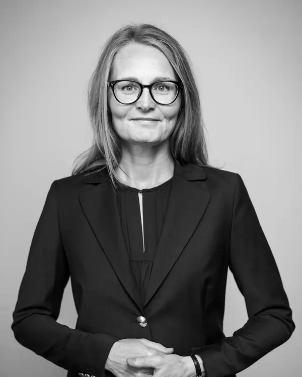 Miriam Vale in a dark jacket and glasses against a plain wall