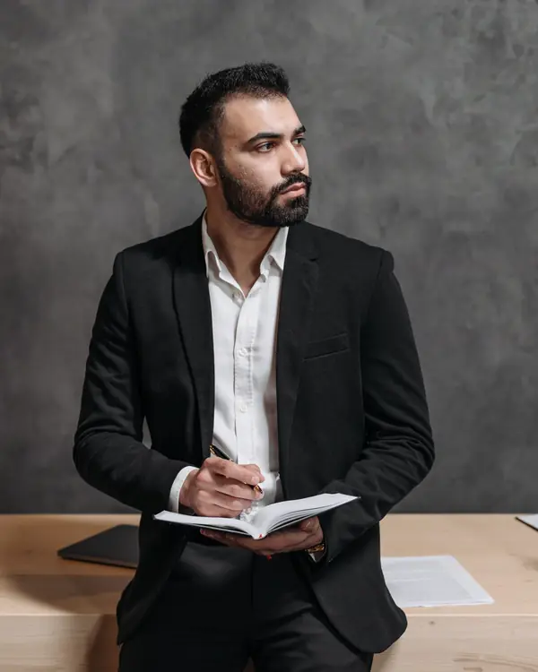 Omar Haddad standing with a notebook in a gray office