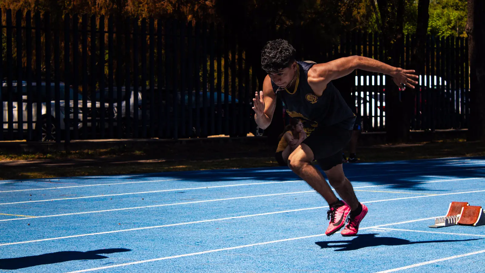 A sprinter drives out of the starting blocks on a running track.