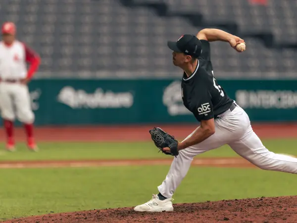 A baseball pitcher releases a pitch from the mound.