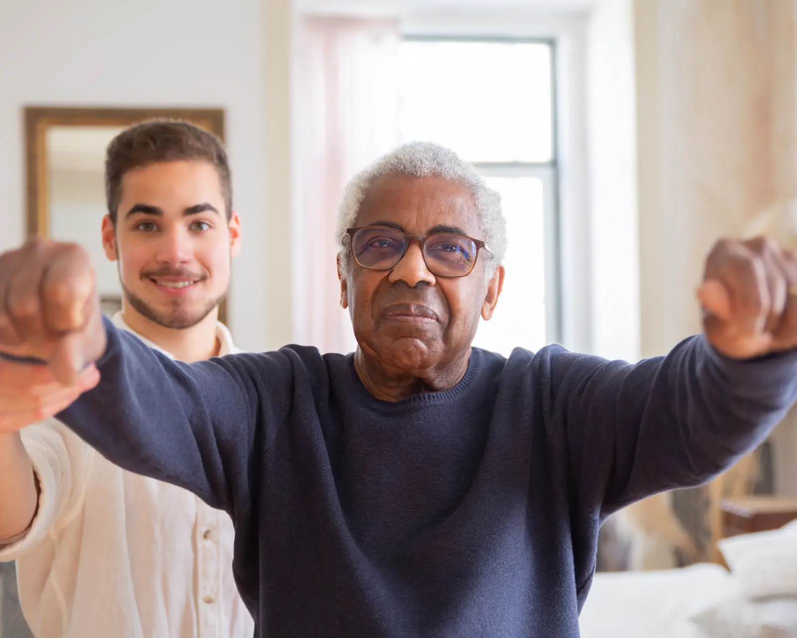 A physical therapist guides an older man through a balance exercise with his arms held out.