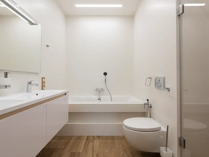 A bright modern bathroom with a tub, vanity and wall-hung toilet