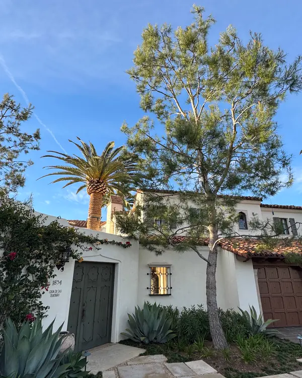 A white Spanish-style San Diego home with palms and agave out front