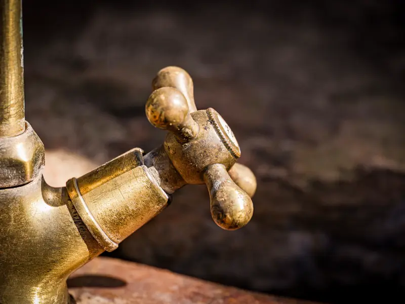 An old brass faucet with a cross handle