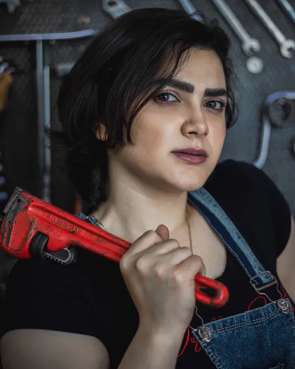 Portrait of Kate Hartley holding a red pipe wrench