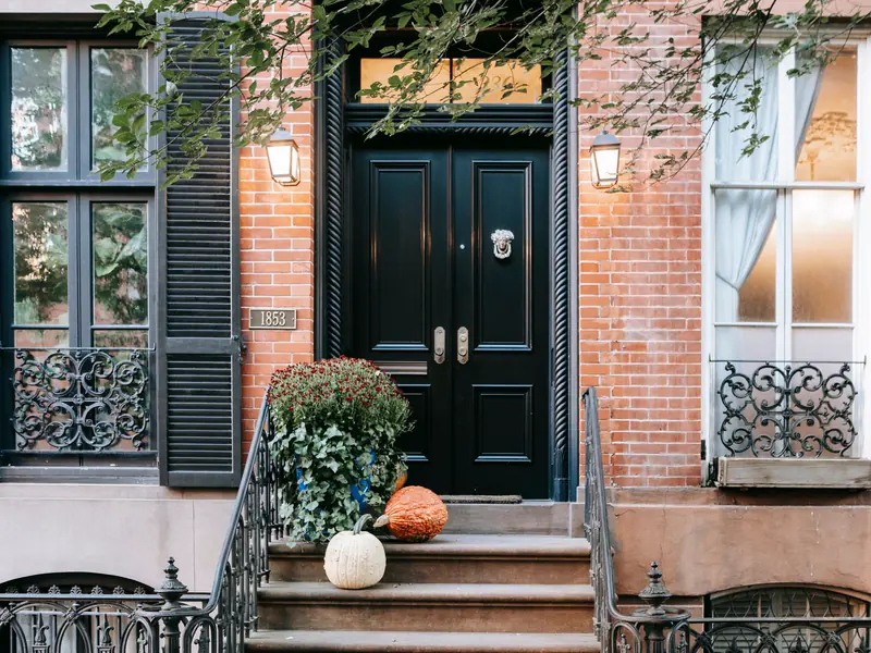 A brick house front door with pumpkins on the steps