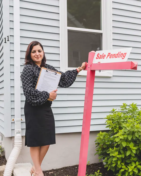 Dana Whitfield standing beside a sale pending sign with a clipboard