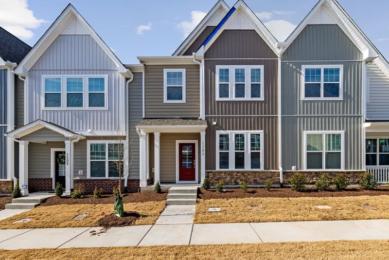 Row of new two-story townhomes with front porches and small lawns