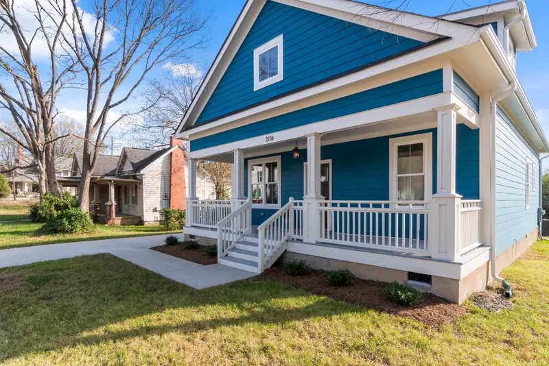 Blue house with a white wraparound front porch and a green lawn
