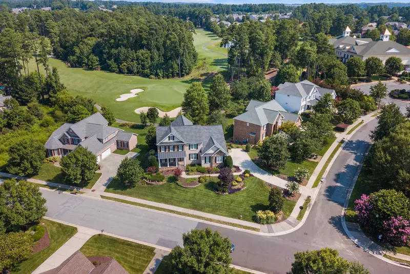 Aerial view of two-story homes along curving streets beside a golf course