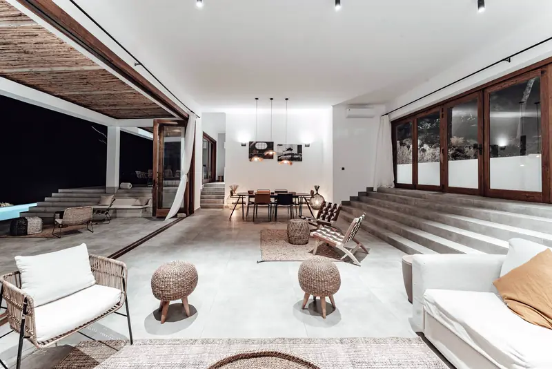 Sunken lounge with white sofas, wooden stools and a cypress pergola outside