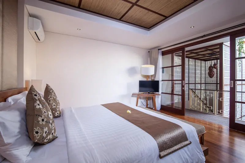 Bedroom suite with white linen, a wooden ceiling and doors to a garden court