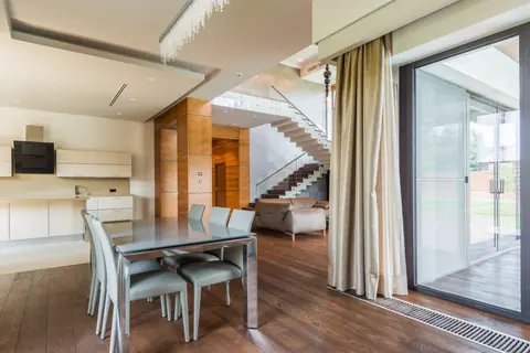 Dining area with a glass table beside floor-to-ceiling sliding doors