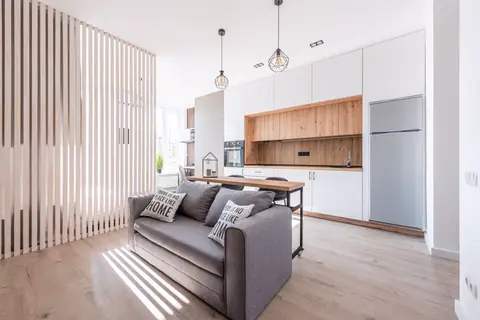 Lower-level media room with a gray sofa and a kitchenette
