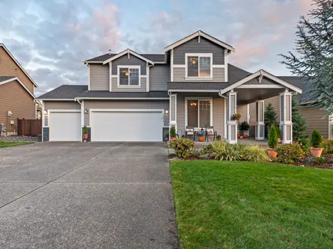 Two-story gray house with a covered porch, a two-car garage and a green lawn